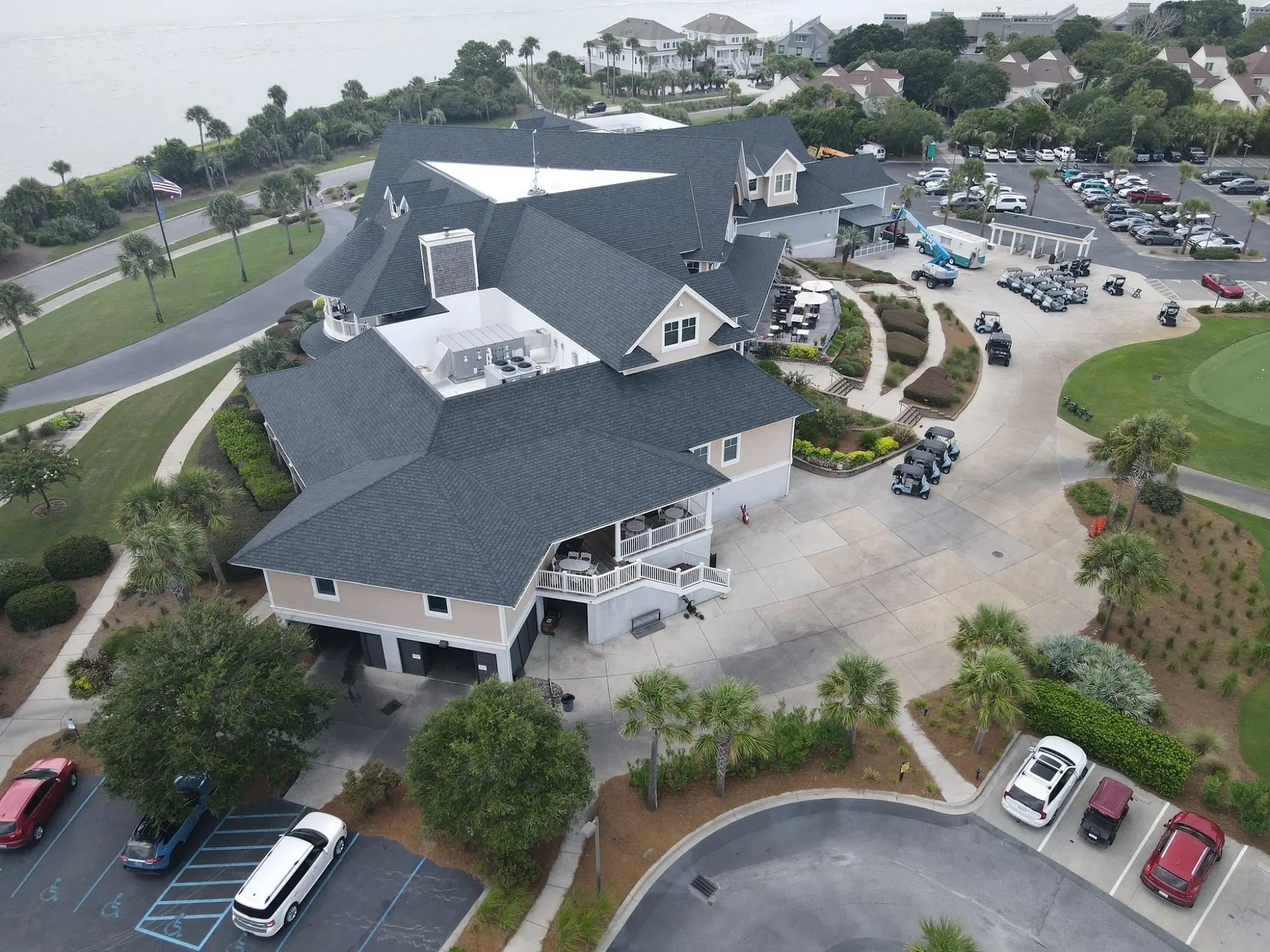 A large, multi-level building with a complex roof structure covered in dark asphalt shingles.